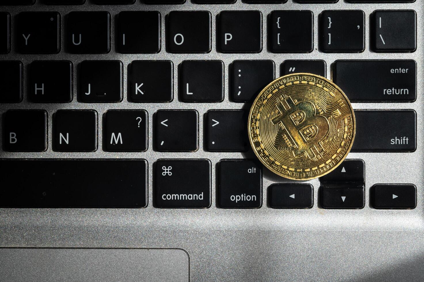 A golden bitcoin token on computer keyboard. photo