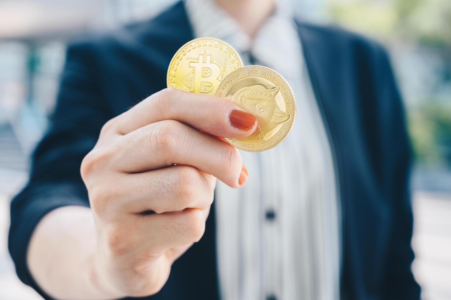 Close up of businesswoman holding Bitcoin and Dogecoin tokens. photo