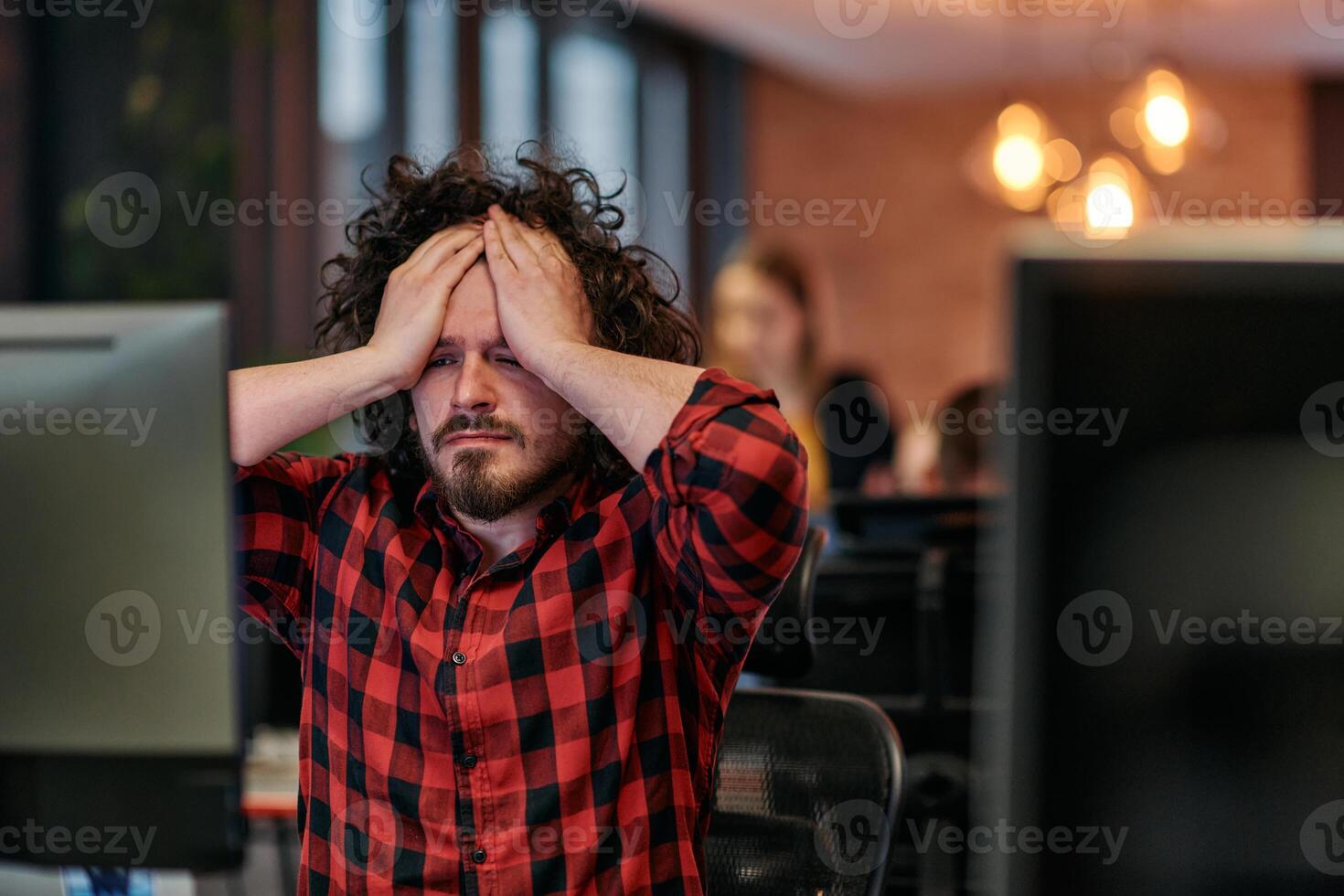 Disappointed Programmer with Messy Hair Looking at Computer Monitor in Office. photo