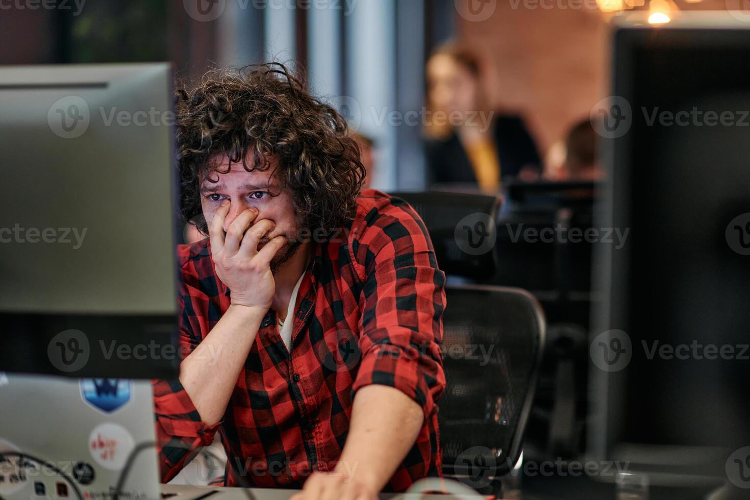 Disappointed Programmer with Messy Hair Looking at Computer Monitor in Office. photo