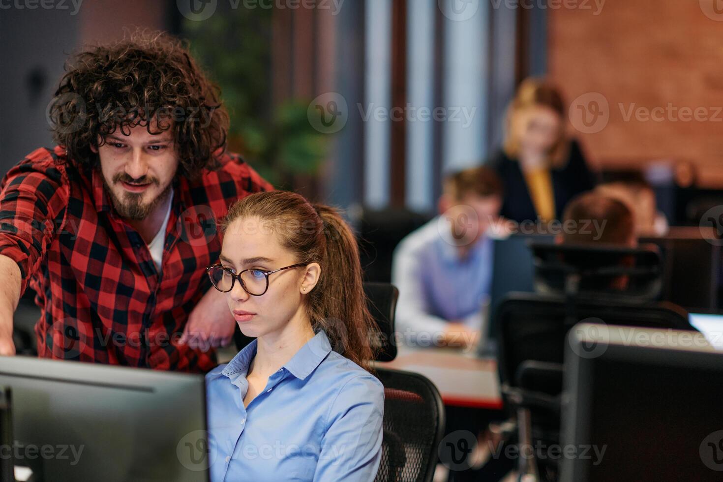 Business colleagues, a man and a woman, engage in discussing business strategies while attentively gazing at a computer monitor, epitomizing collaboration and innovation photo