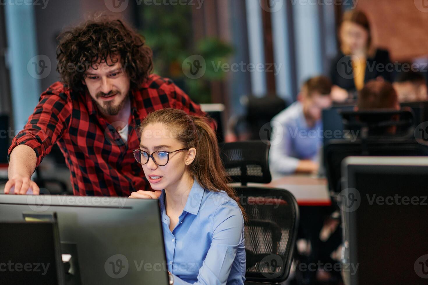 Business colleagues, a man and a woman, engage in discussing business strategies while attentively gazing at a computer monitor, epitomizing collaboration and innovation photo