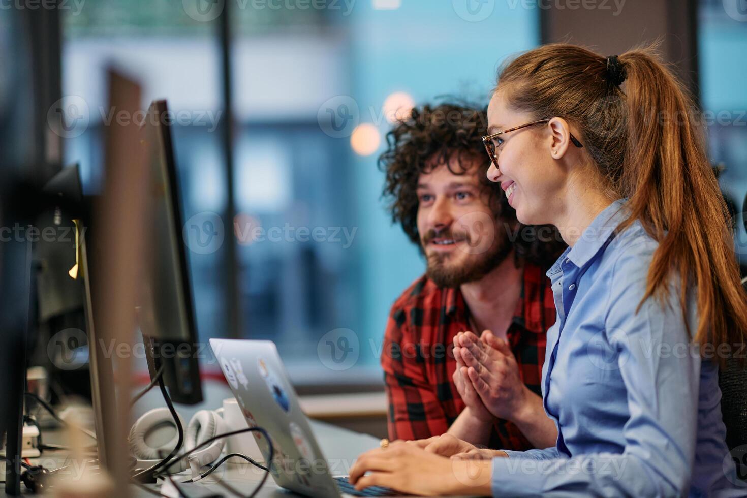 Business colleagues, a man and a woman, engage in discussing business strategies while attentively gazing at a computer monitor, epitomizing collaboration and innovation photo