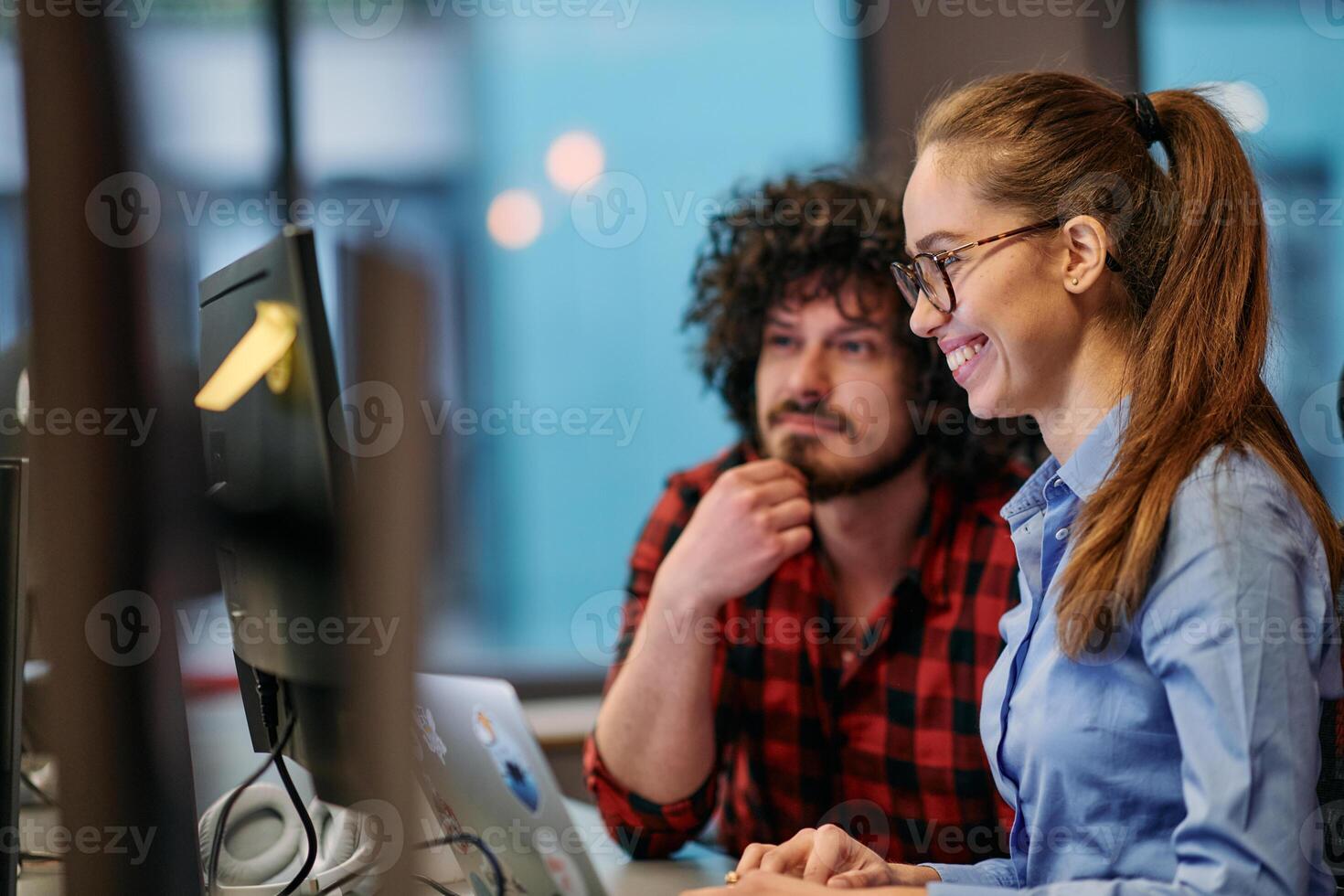 Business colleagues, a man and a woman, engage in discussing business strategies while attentively gazing at a computer monitor, epitomizing collaboration and innovation photo