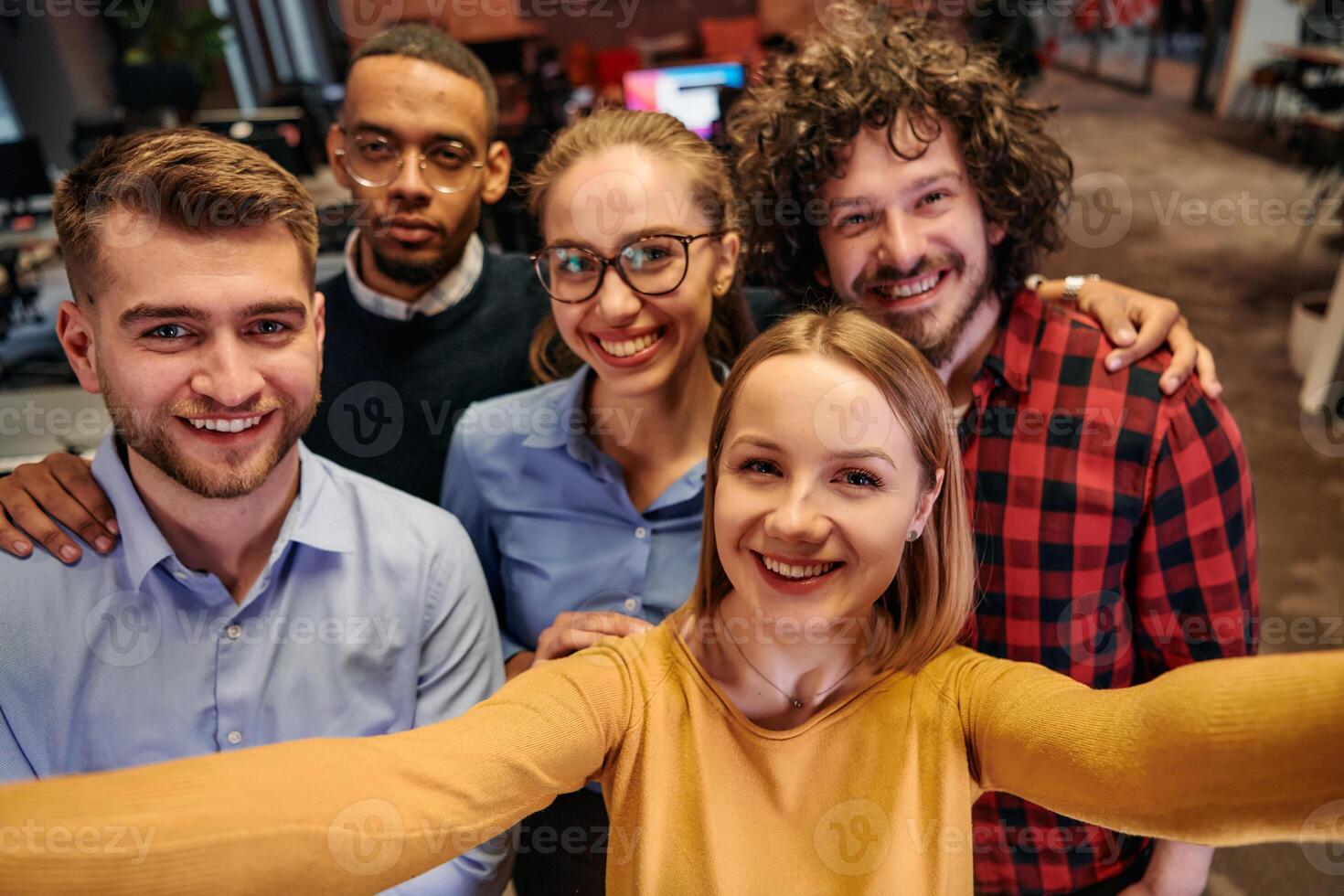 A diverse group of business professionals take a break from their tasks in a modern startup office to capture a creative selfie, showcasing teamwork and a vibrant workplace culture photo