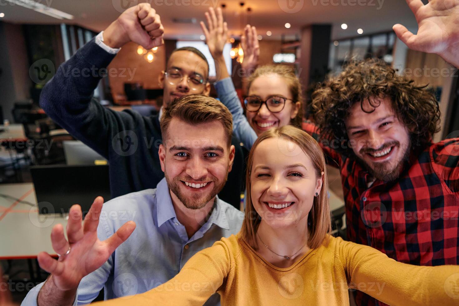 A diverse group of business professionals take a break from their tasks in a modern startup office to capture a creative selfie, showcasing teamwork and a vibrant workplace culture photo