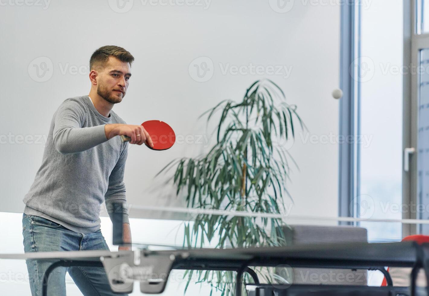 Business colleagues take a break from work to enjoy a game of table tennis, fostering teamwork and camaraderie in the workplace photo