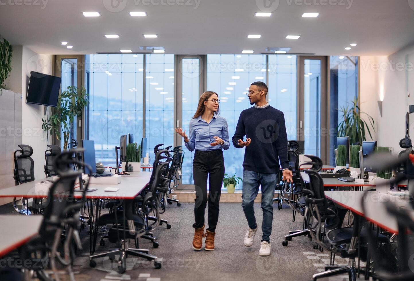 Dynamic Business Collaboration. Blonde Businesswoman and African American Colleague in Modern Office Setting. photo