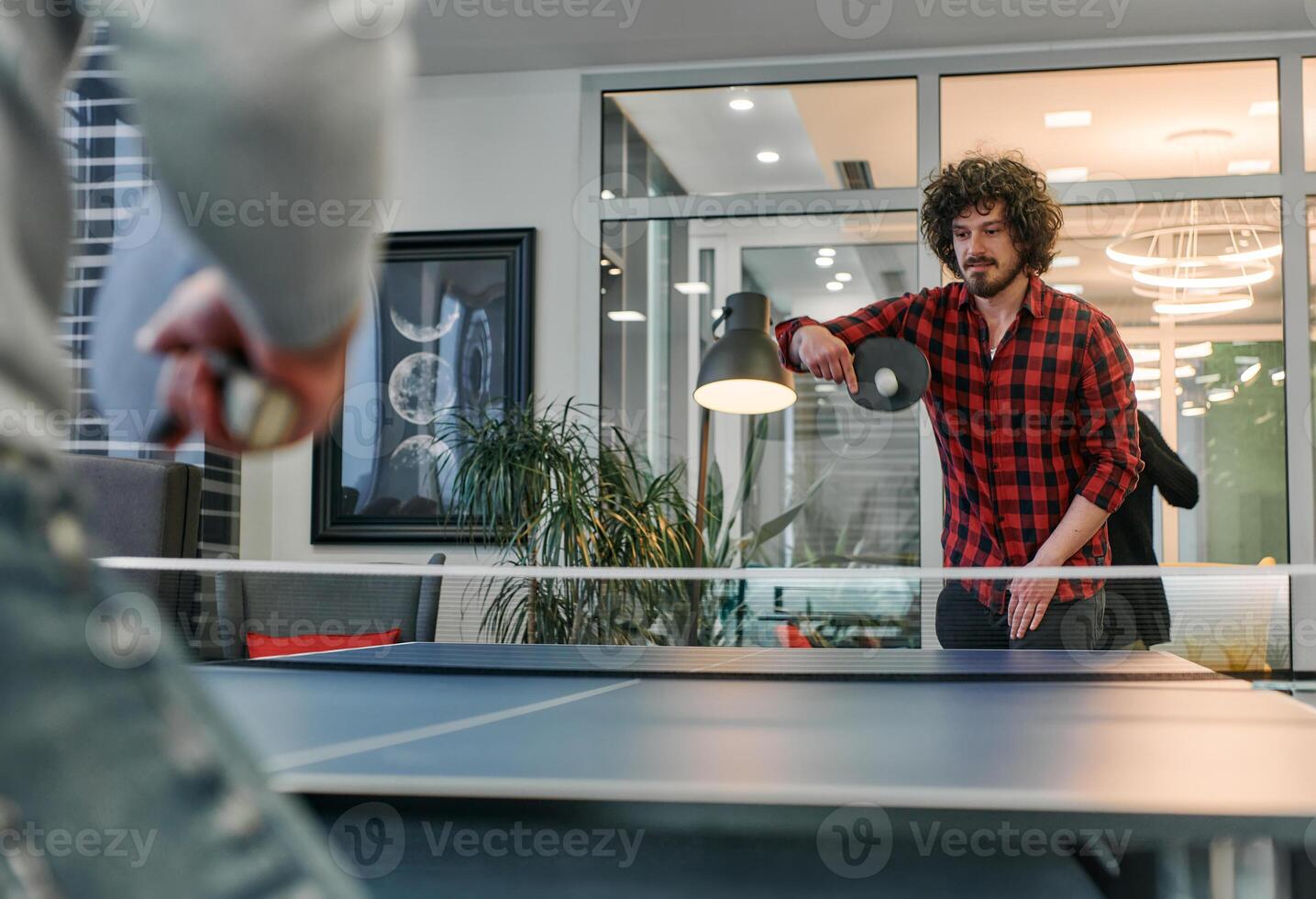Business colleagues take a break from work to enjoy a game of table tennis, fostering teamwork and camaraderie in the workplace photo