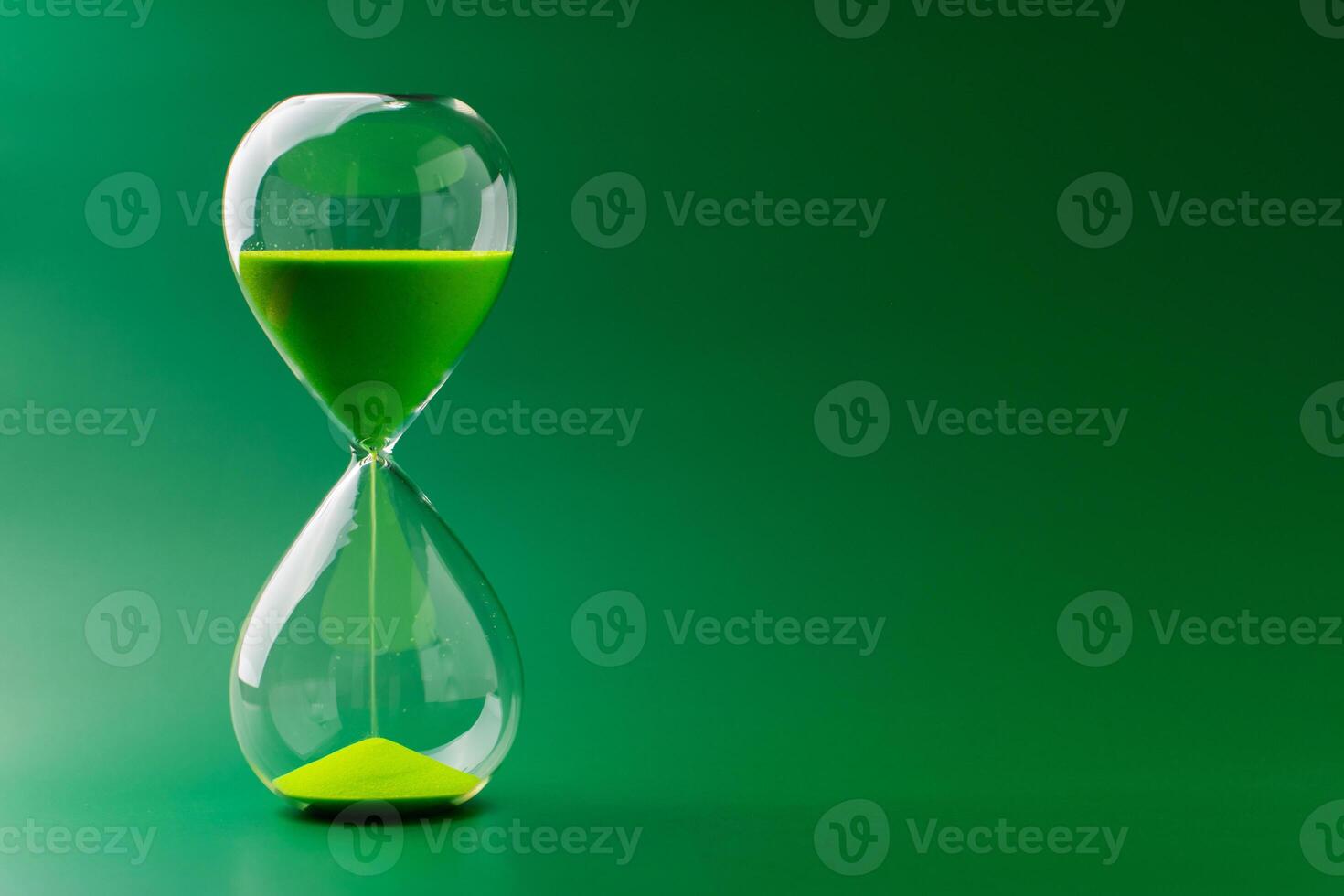 Hourglass standing still, working with time limit and limits, photo in studio on green background