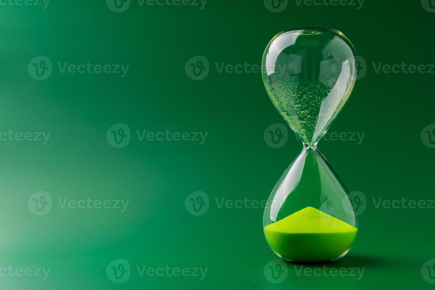 Hourglass standing still on green background, time concept and definition of oscillating period. photo