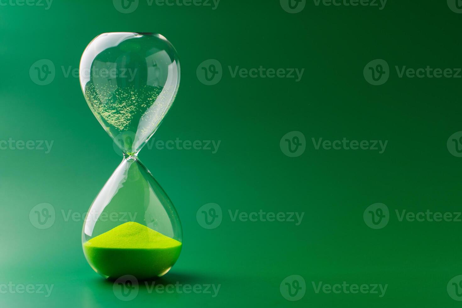 Hourglass standing still on green background, time concept and definition of oscillating period. photo