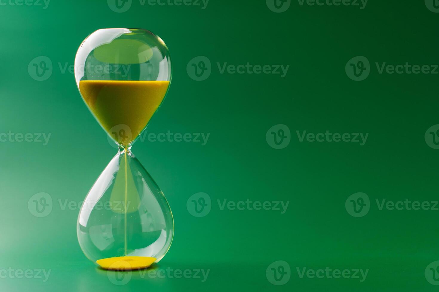 Hourglass standing still, working with time limit and limits, photo in studio on green background