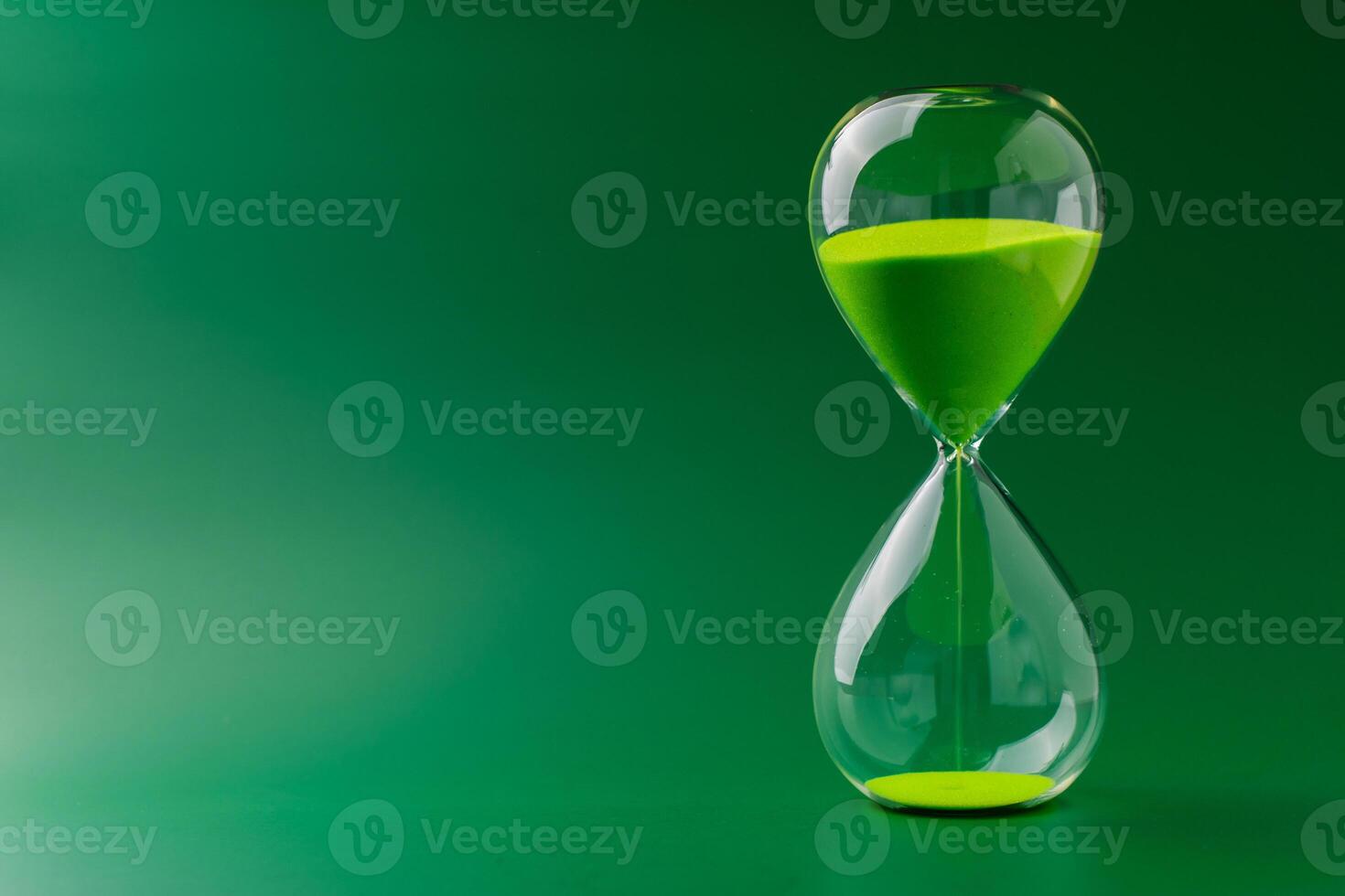 Hourglass standing still, working with time limit and limits, photo in studio on green background