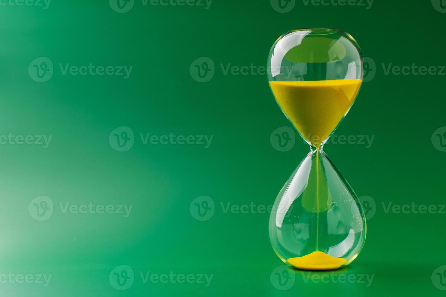 Hourglass standing still on green background, time concept and definition of oscillating period. photo