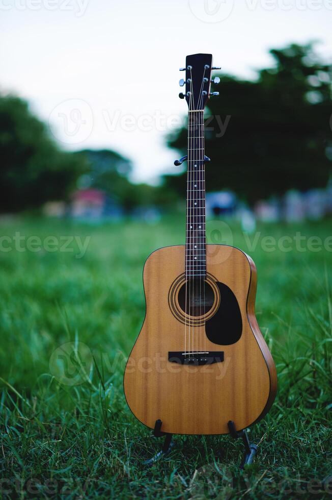 Acoustic guitar, stringed musical instrument, placed in the grass, classical guitar, playing music and relaxing. photo