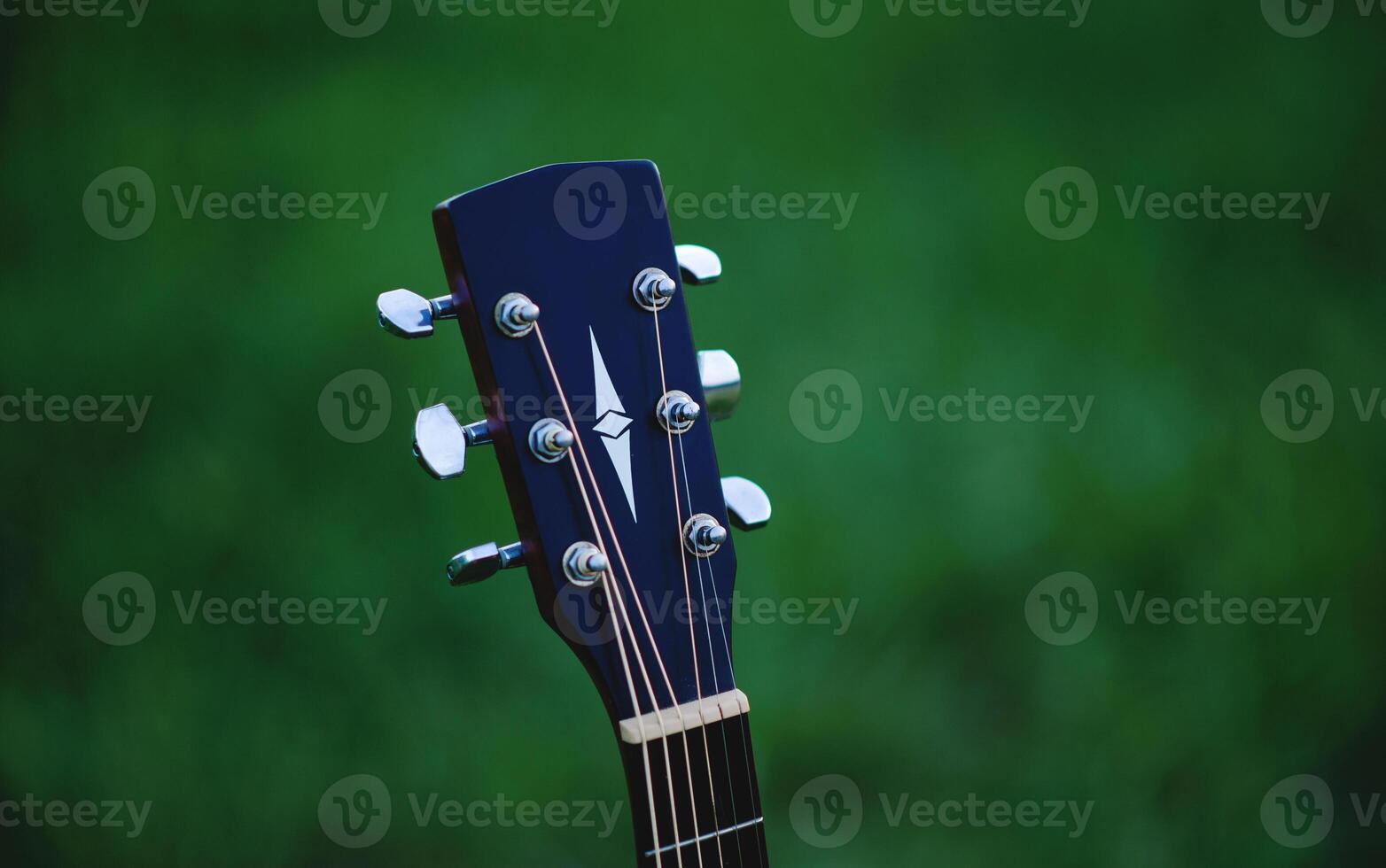 Acoustic guitar, stringed musical instrument, placed in the grass, classical guitar, playing music and relaxing. photo