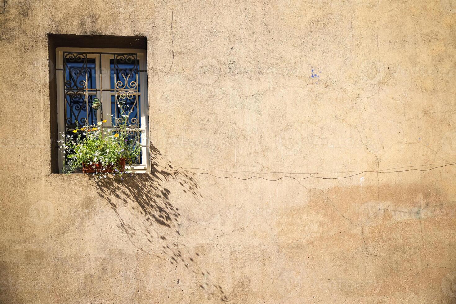 wall of a house with a window, flowers on the windowsill rustic style house facade photo