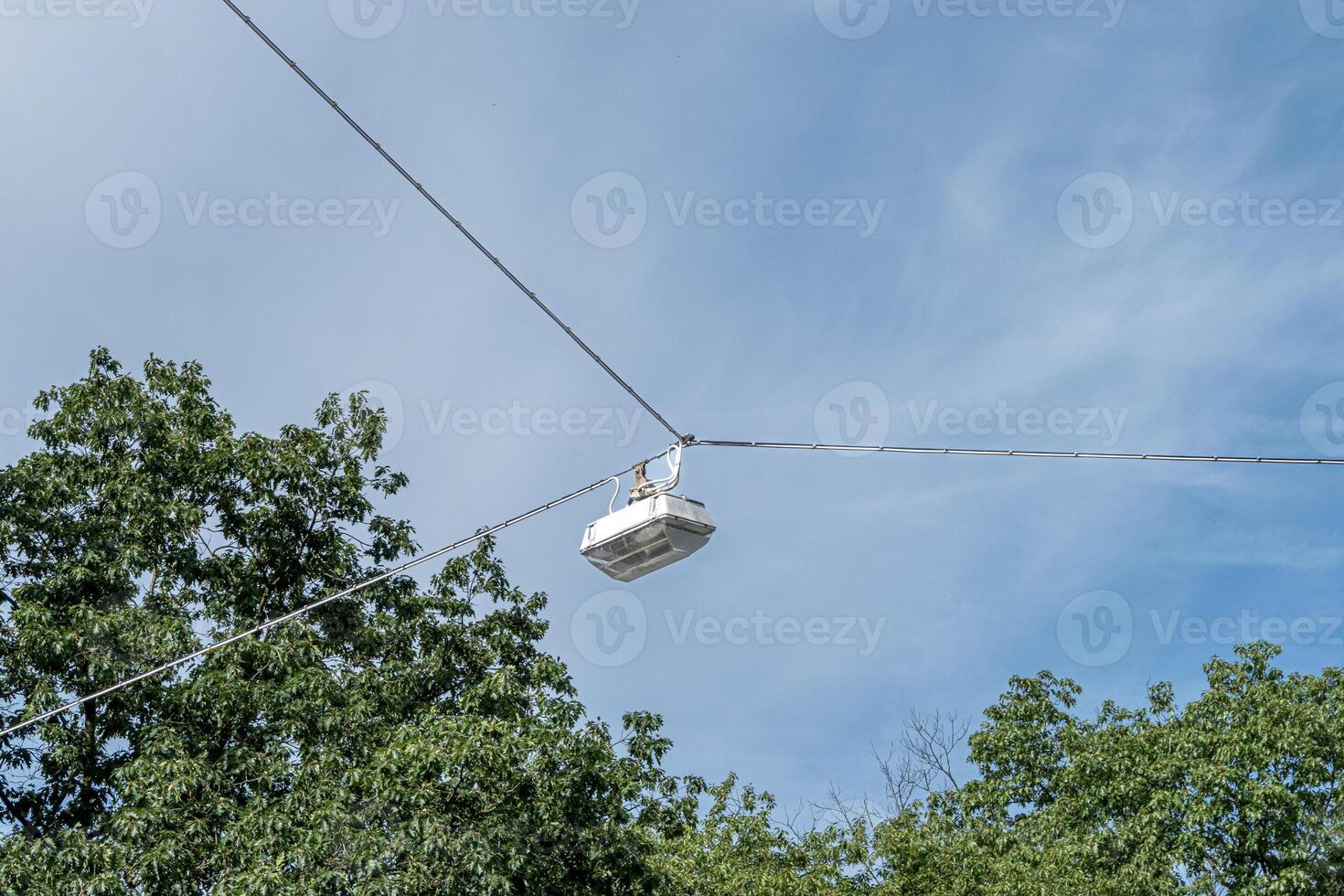 hanging street lamp between sky and trees photo