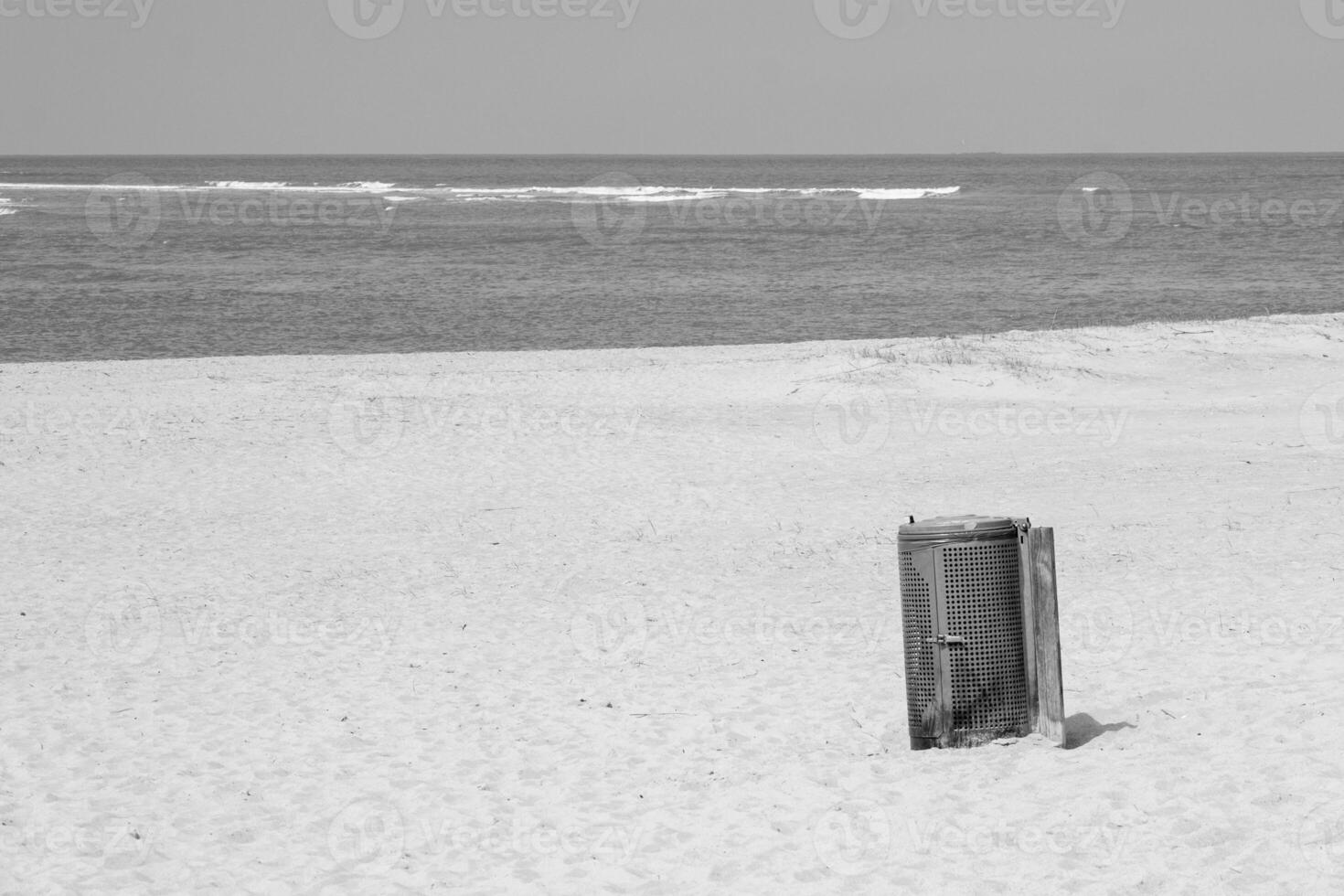sandy beach with garbage can on the french north sea, greyscale shot photo