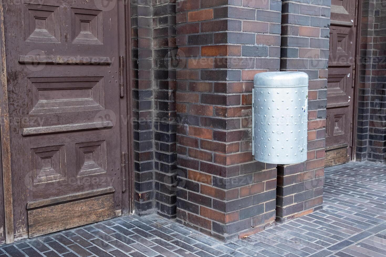 modern stainless steel wastepaper basket on an old brick building photo