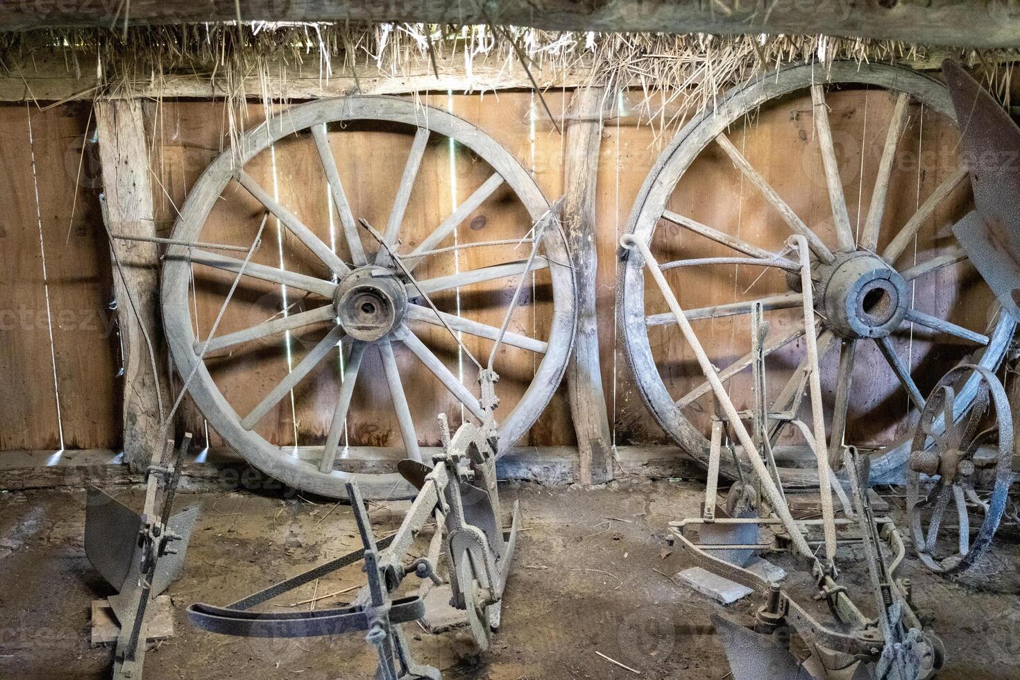 wooden spoked wheels and plows in barn photo