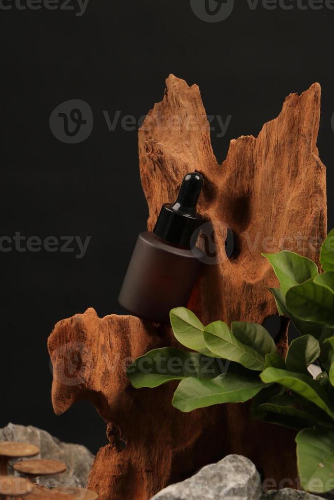 Matte Amber Dropper Bottle with Black Cap on Rustic Wood and Leaf Background photo