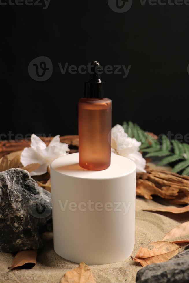 Amber Dropper Bottle on White Pedestal with Natural Elements photo