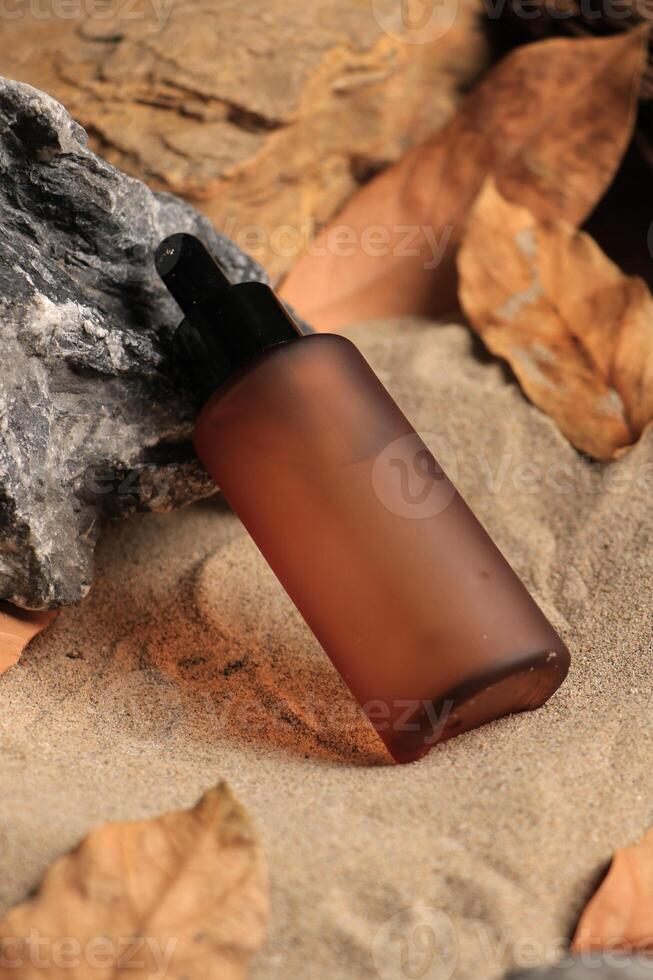 Amber Dropper Bottle with Natural Elements on Sandy Background photo