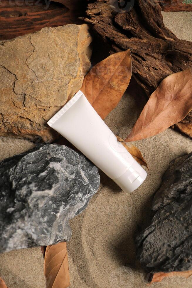 White Cosmetic Tube on Sandy Background with Natural Elements photo