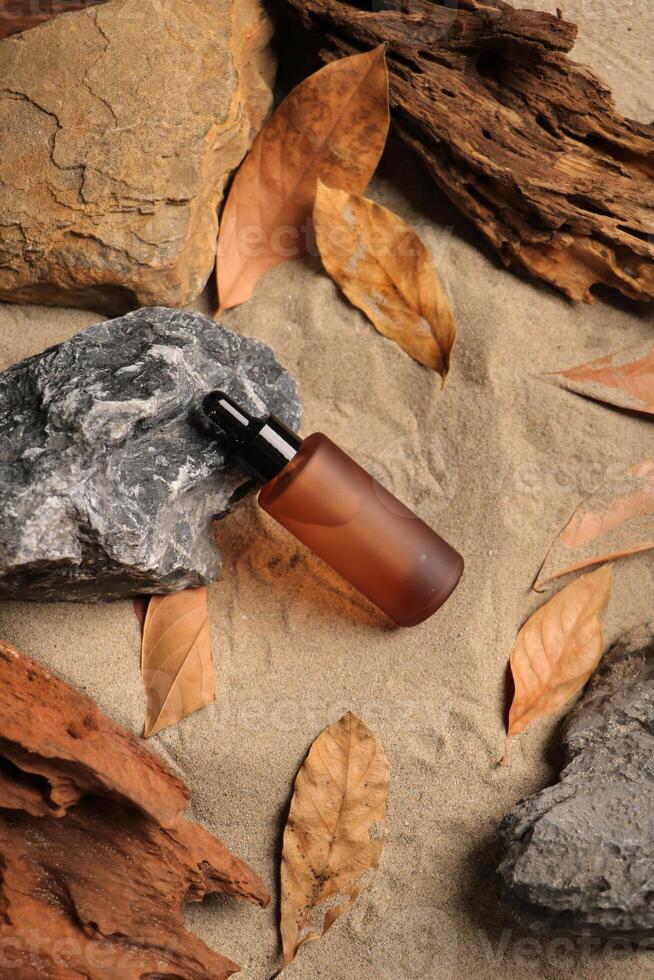 Amber Dropper Bottle with Natural Elements on Sandy Background photo