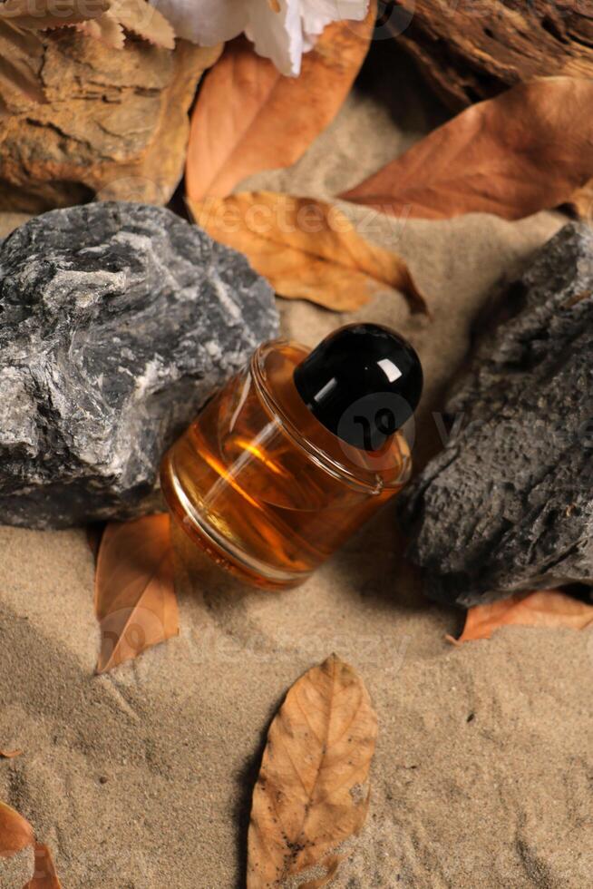 Luxurious Amber Glass Bottle on Sandy Natural Background photo