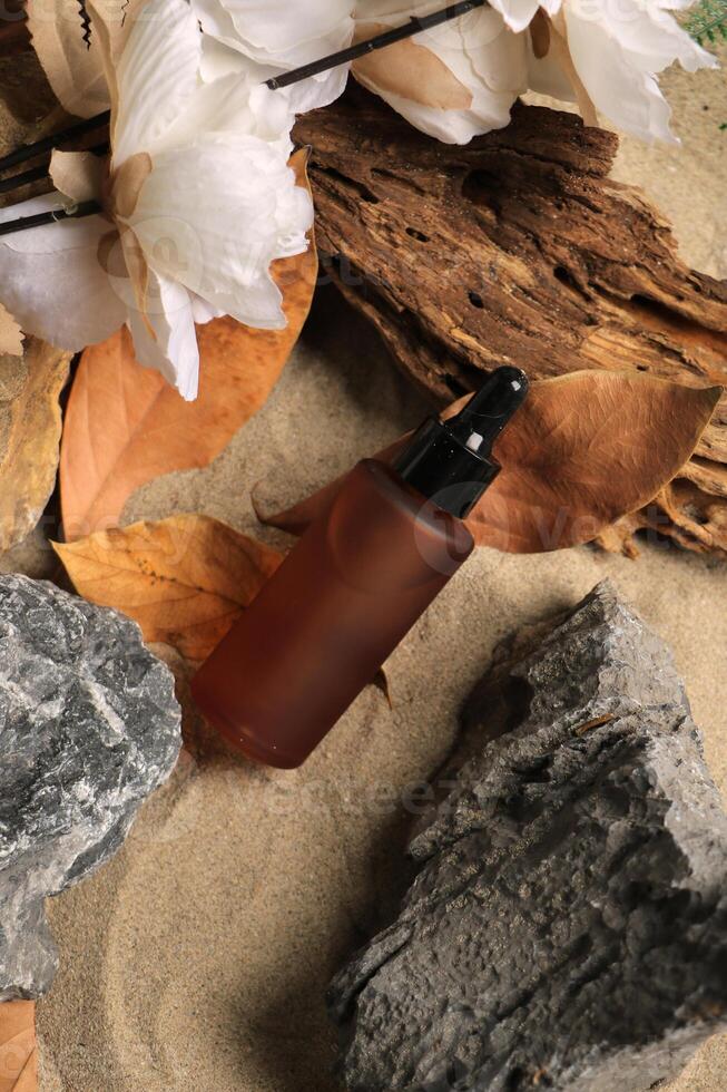 Amber Dropper Bottle with Natural Elements on Sandy Background photo