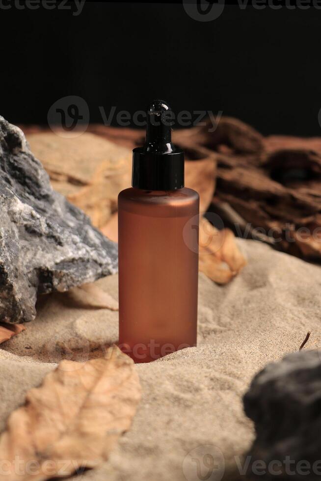 Amber Dropper Bottle on Sandy Background with Autumn Leaves and Rocks photo