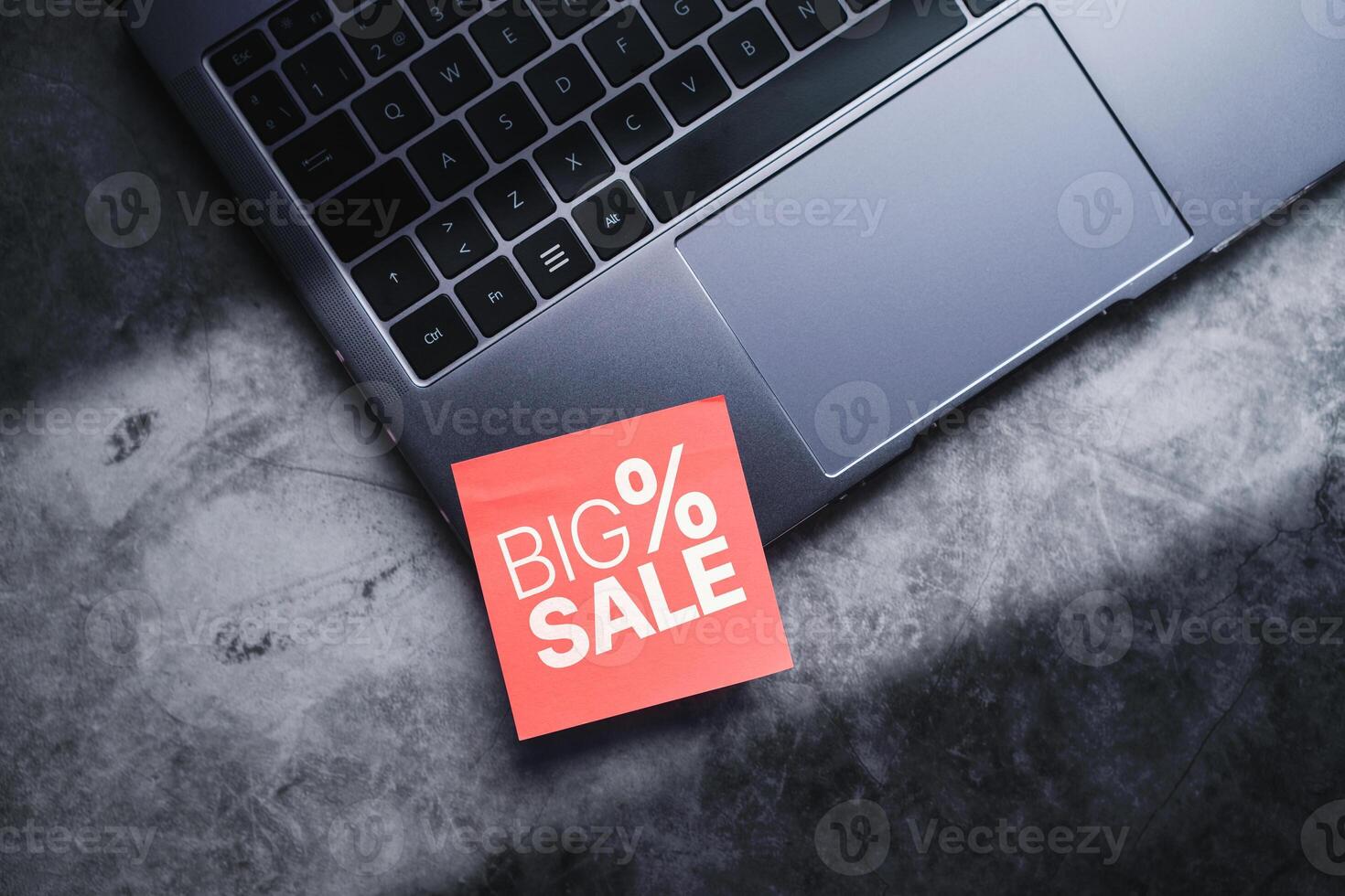 Laptop with a red adhesive note with big sale on it. Discounts, online shopping. Desktop view with copy space. photo