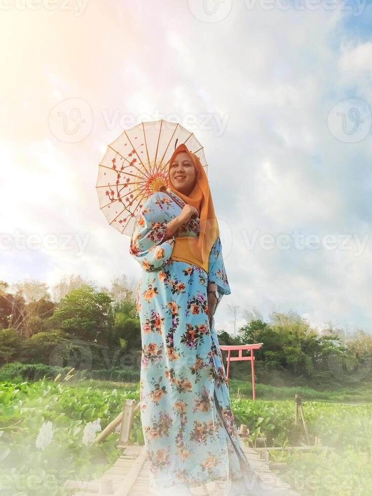Charming Japanese woman wearing a kimono and holding an umbrella amidst stunning nature, captured at sunset photo