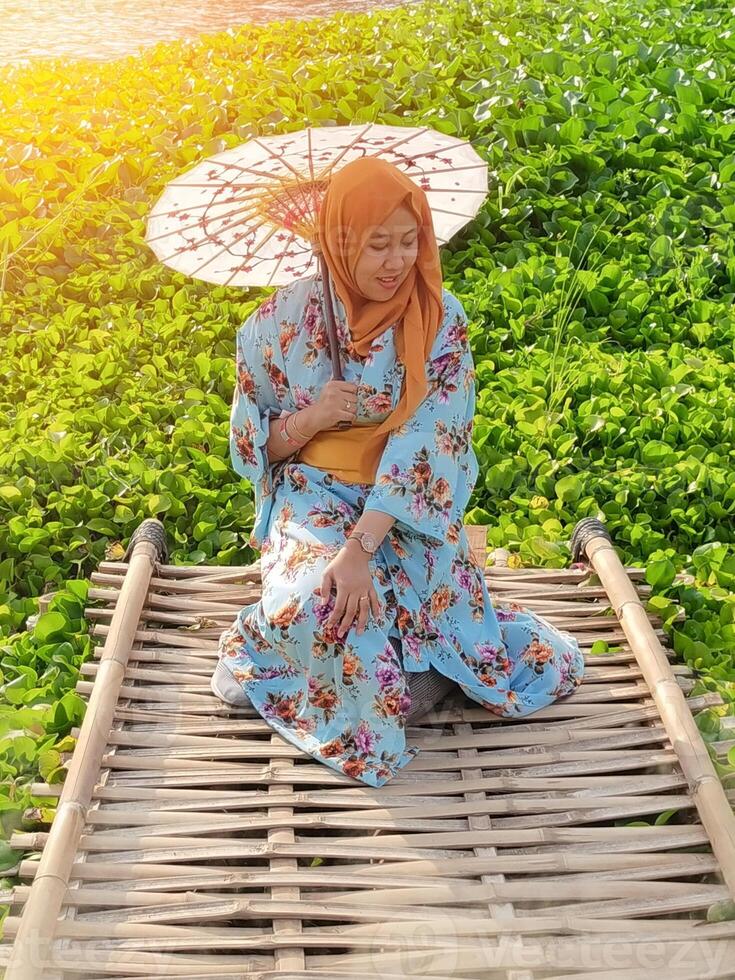 Charming Japanese woman wearing a kimono and holding an umbrella amidst stunning nature, captured at sunset photo