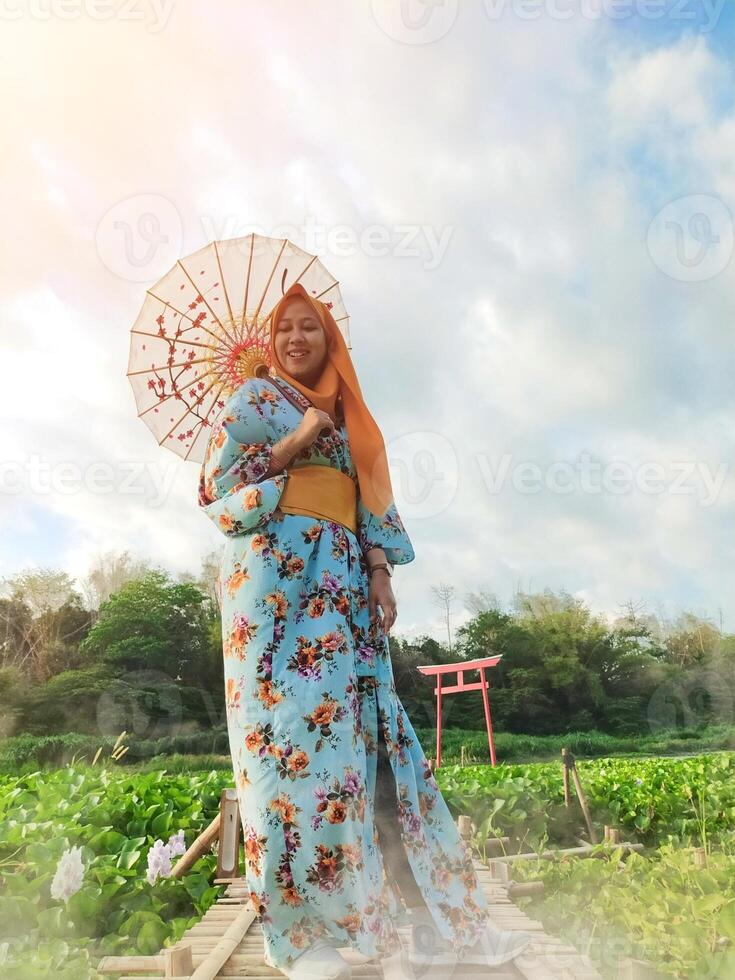 Charming Japanese woman wearing a kimono and holding an umbrella amidst stunning nature, captured at sunset photo