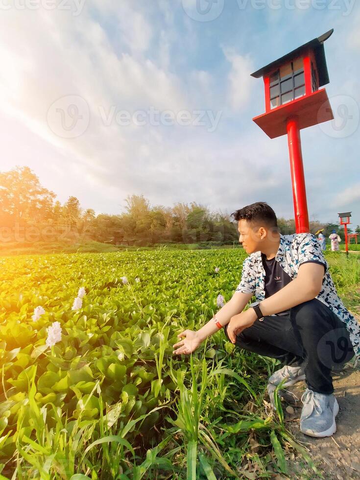Cool asian man dressed in shirt is among the nature of amazing green leaves, enjoying a holiday looking for tranquility photo