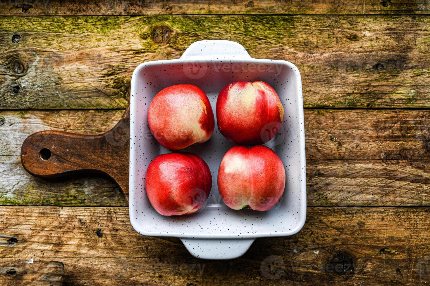 nectarine in a white ceramic bowl on a wooden background on a kitchen board photo