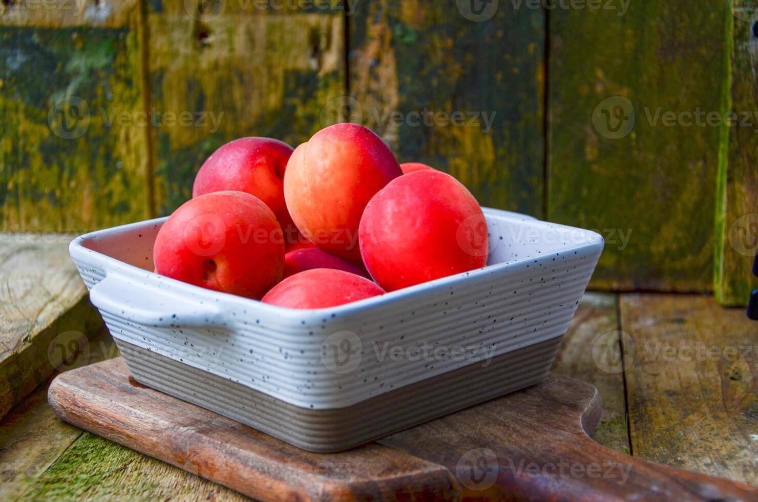 apricots in a white ceramic bowl on a wooden background on a kitchen board photo