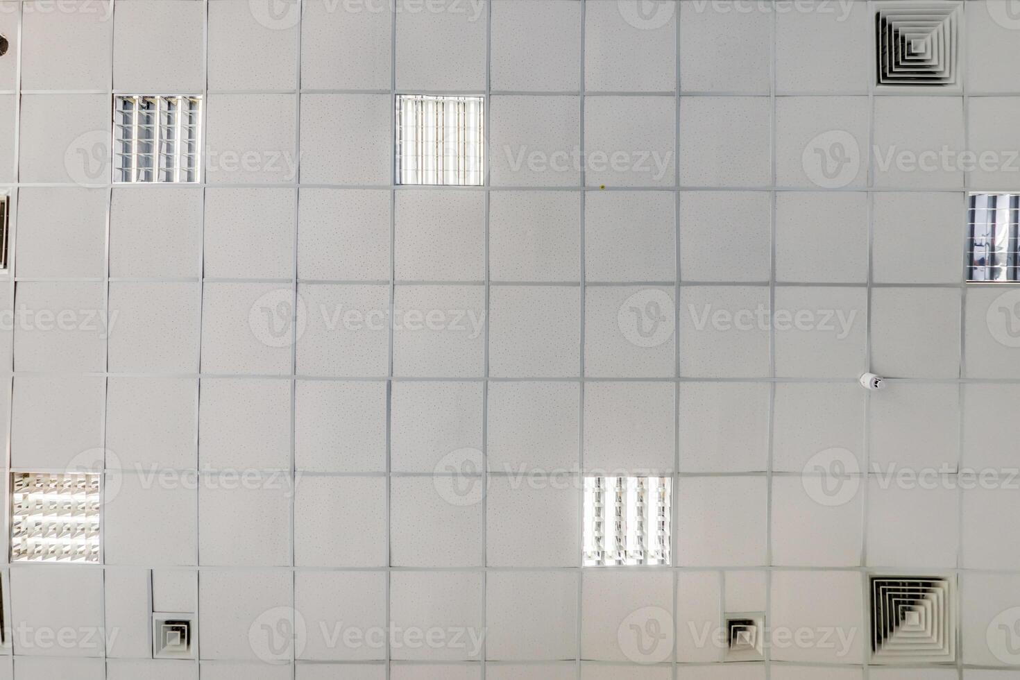 cassette stretched or suspended ceiling with square halogen spots lamps and drywall construction in empty room in house or office. Looking up view photo