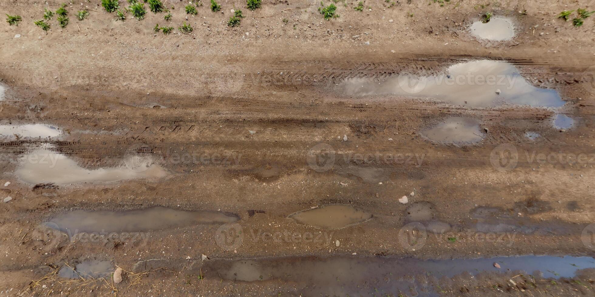 view from above on texture of wet gravel road with puddles after rain photo