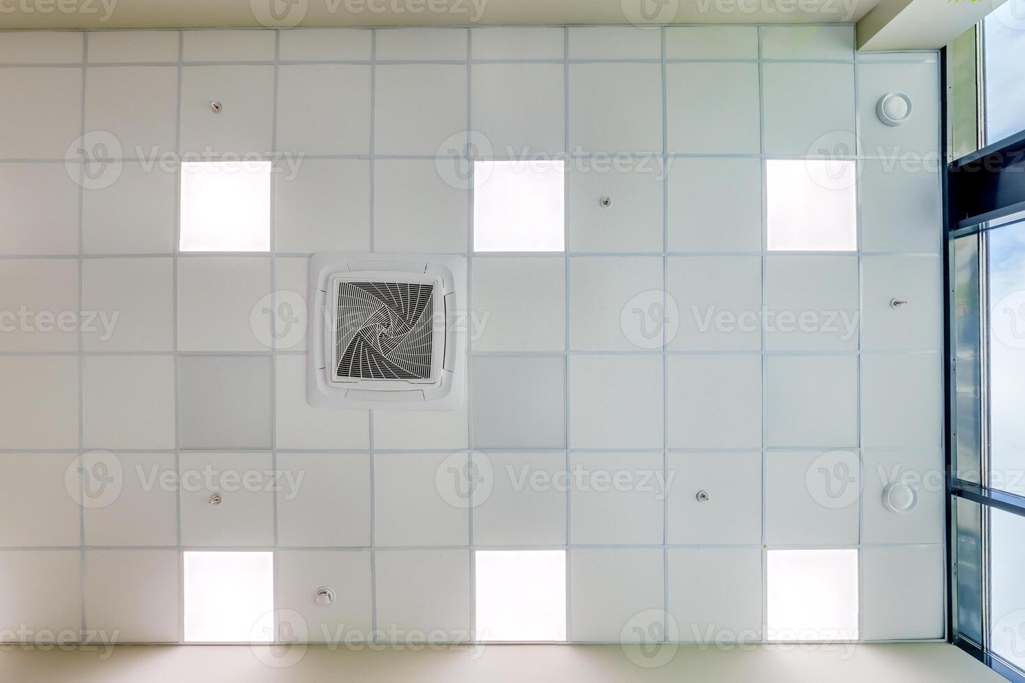 cassette stretched or suspended ceiling with square halogen spots lamps and drywall construction in empty room in house or office. Looking up view photo