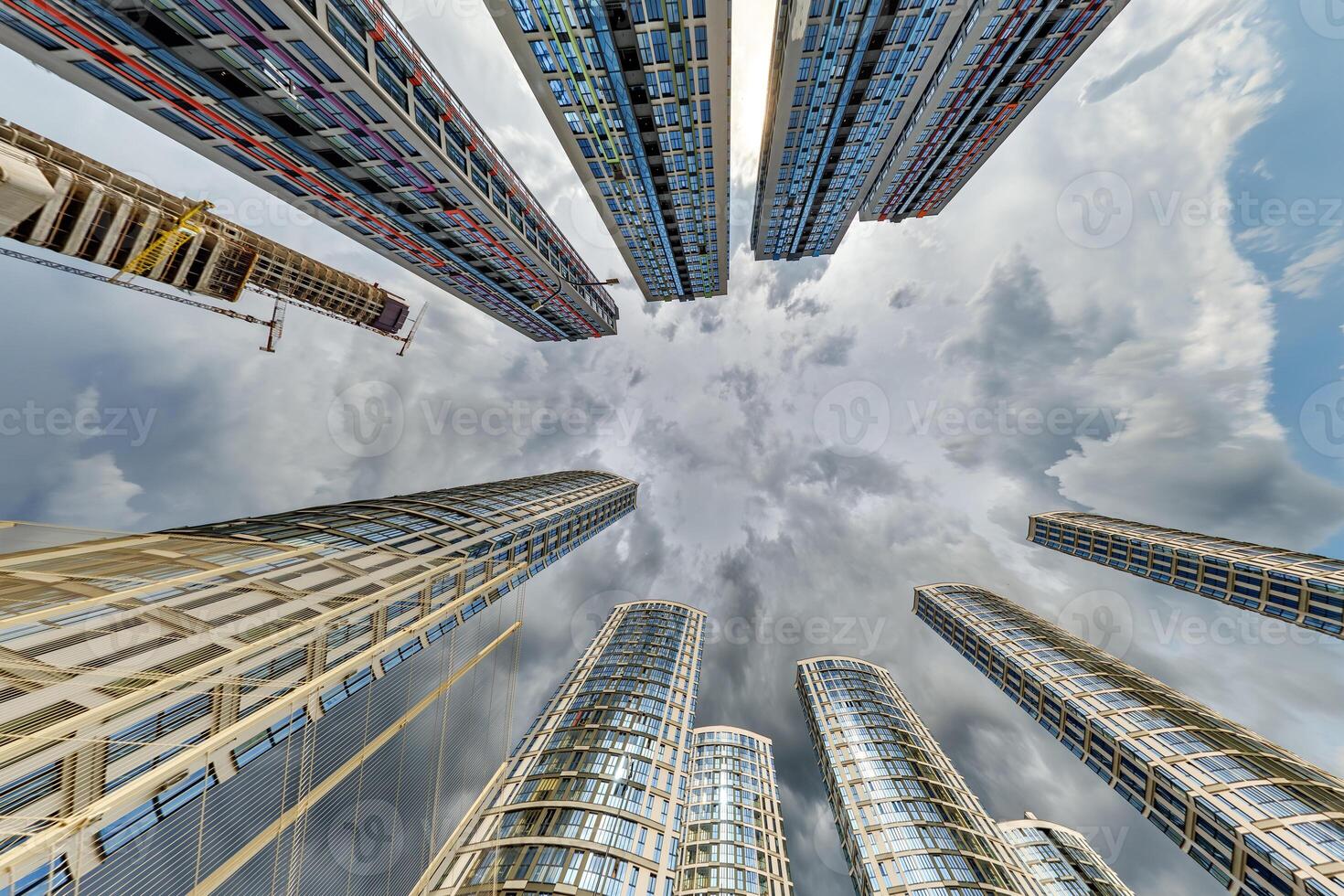 view from below into storm sky with dark clouds of large modern skyscraper residential complex photo