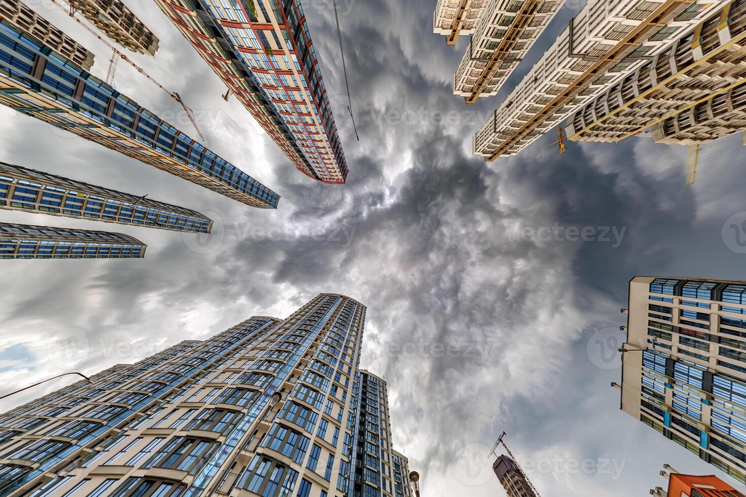 view from below into storm sky with dark clouds of large modern skyscraper residential complex photo