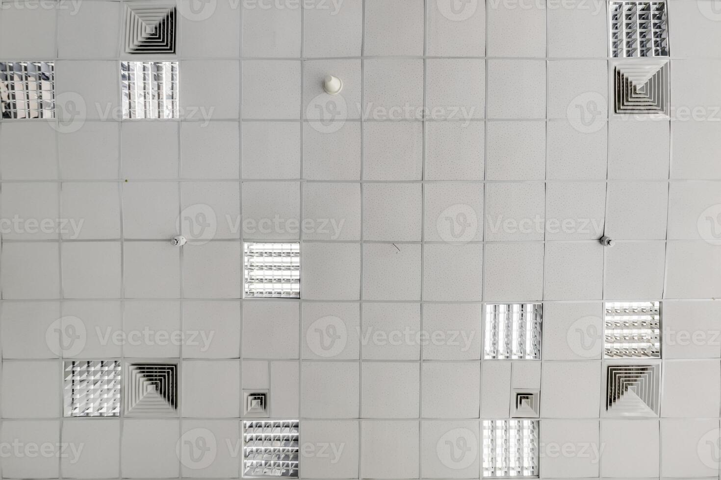 cassette stretched or suspended ceiling with square halogen spots lamps and drywall construction in empty room in house or office. Looking up view photo
