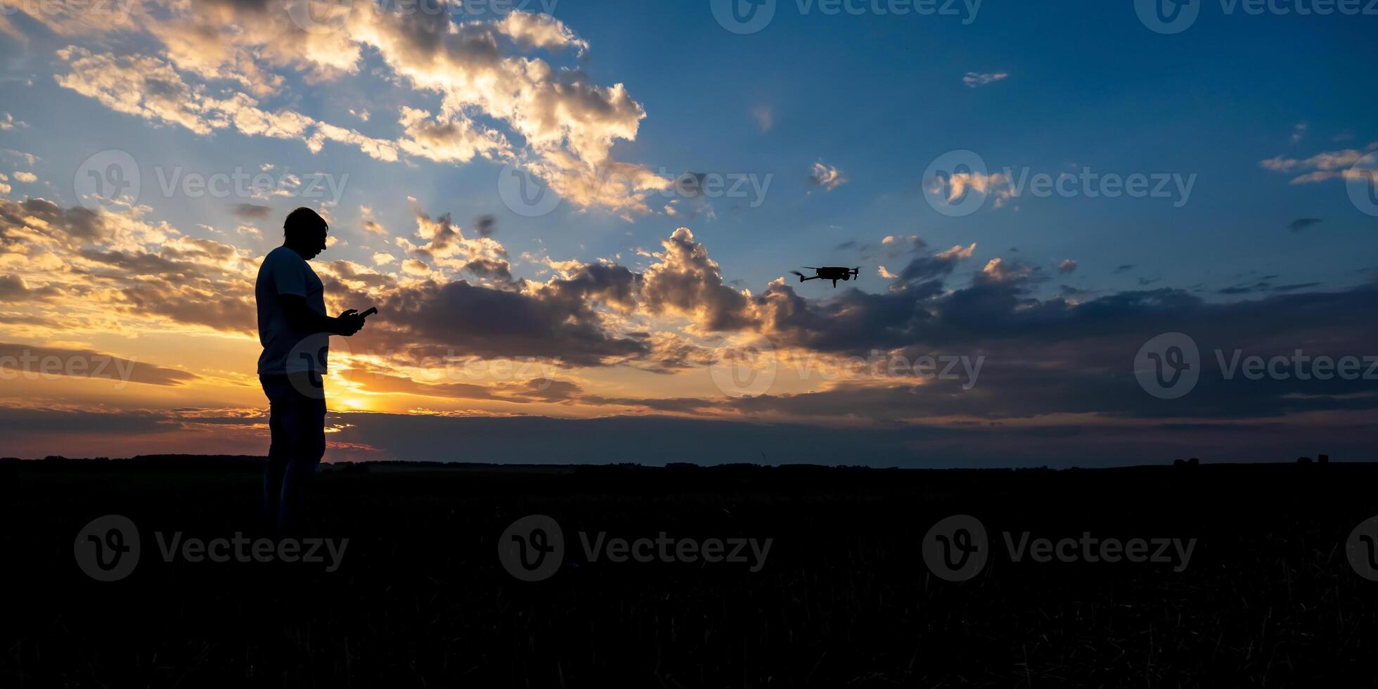 silhouette of man controlling drone on sunset background photo