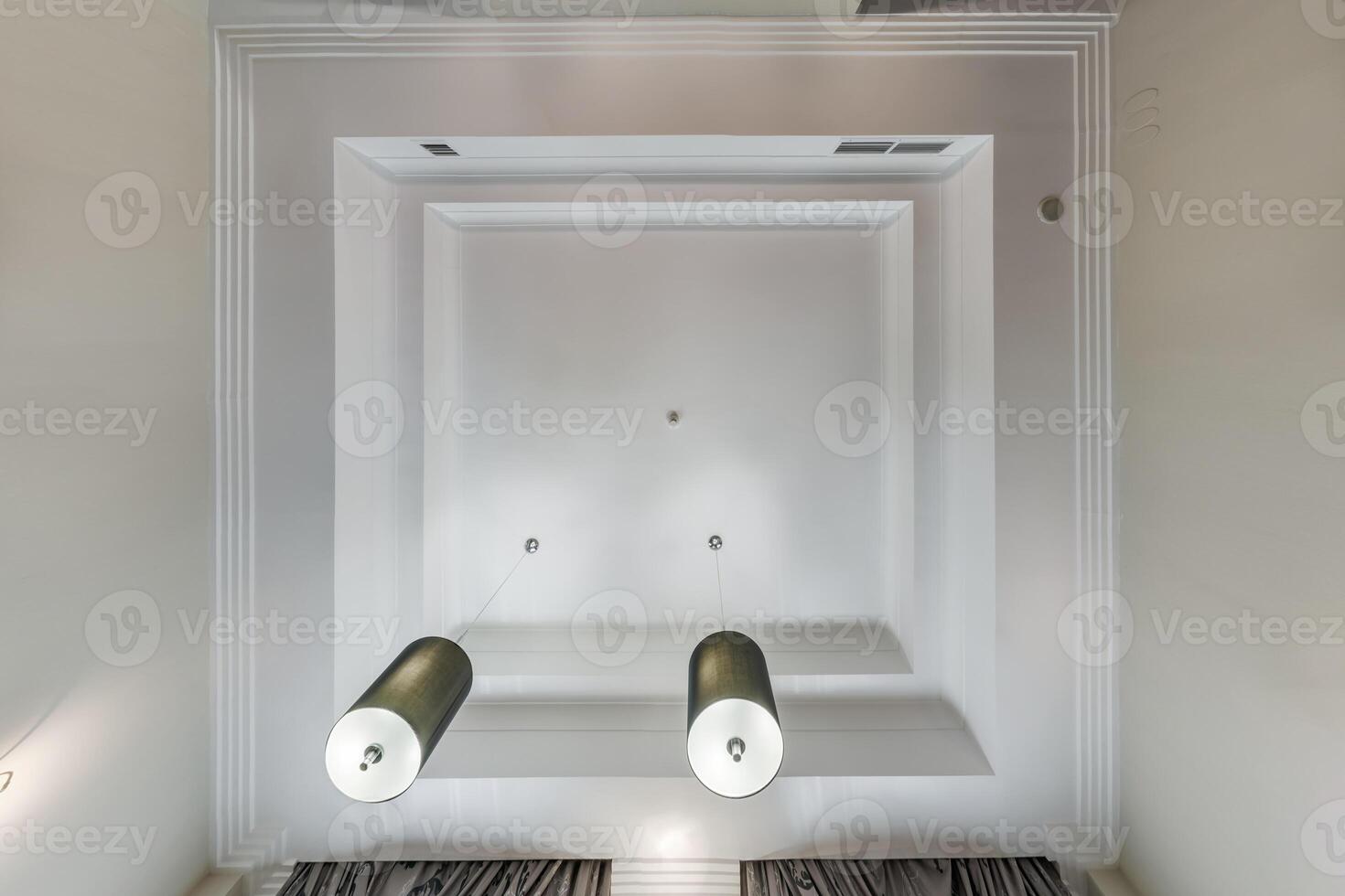 suspended ceiling with halogen spots lamps and drywall construction in empty room in apartment or house. Stretch ceiling white and complex shape. photo