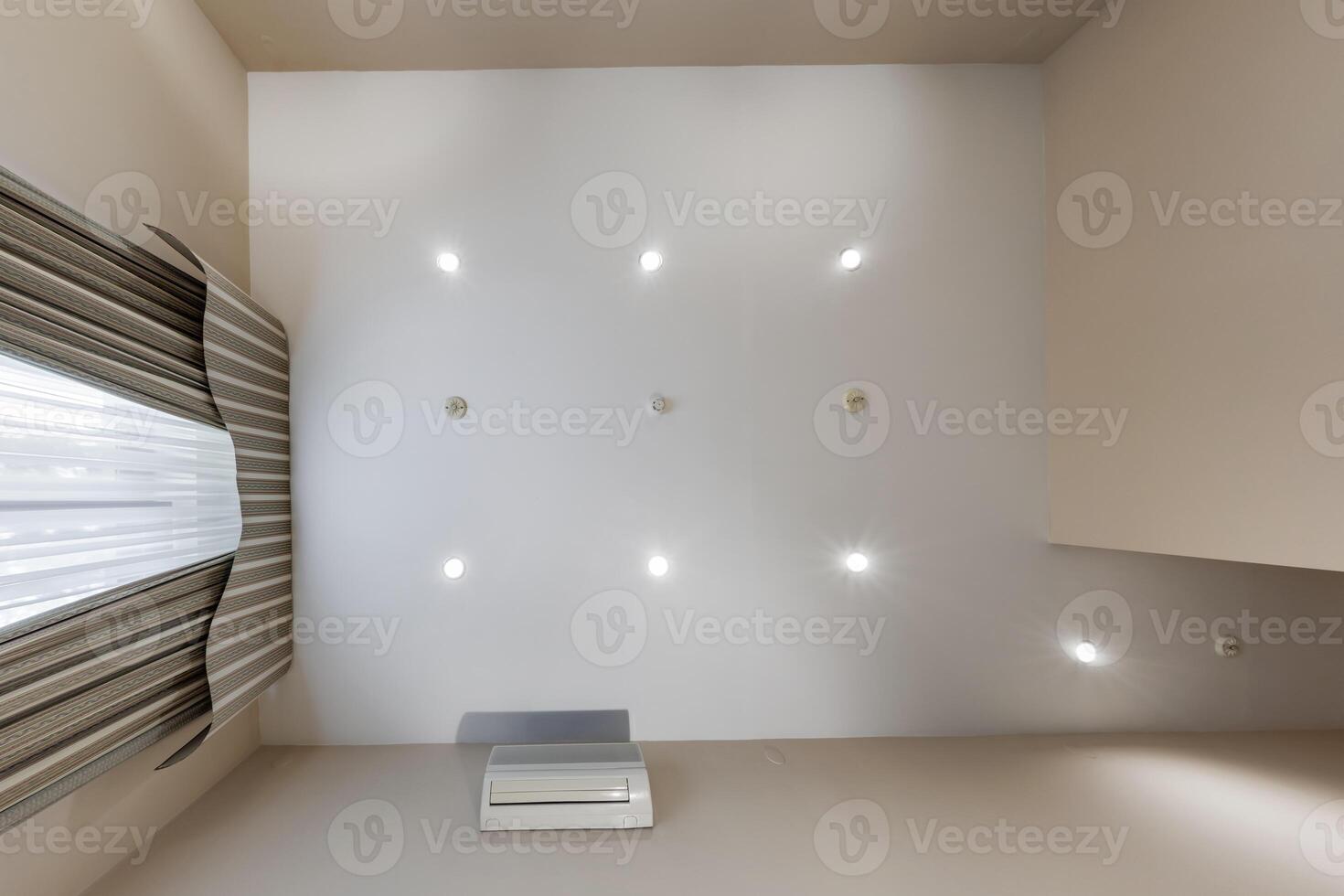 suspended ceiling with halogen spots lamps and drywall construction in empty room in apartment or house. Stretch ceiling white and complex shape. photo